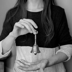 Amanda holding a brass bell, which she uses in her creative practice to enter a state of creative flow.